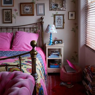 bedroom with white wall frames on wall metal bed with pink designed cushions