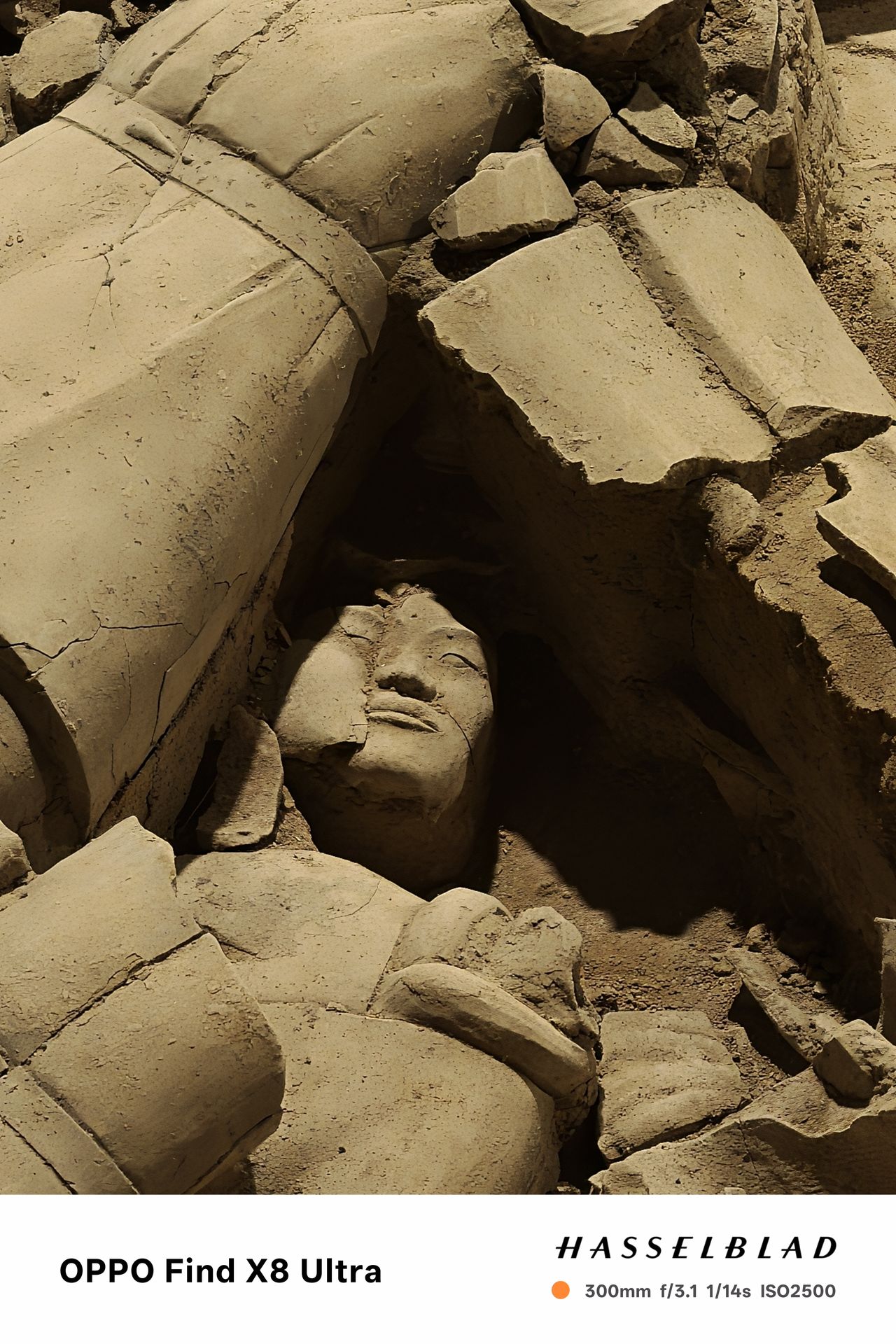 A face on the ground surrounded by other ruins