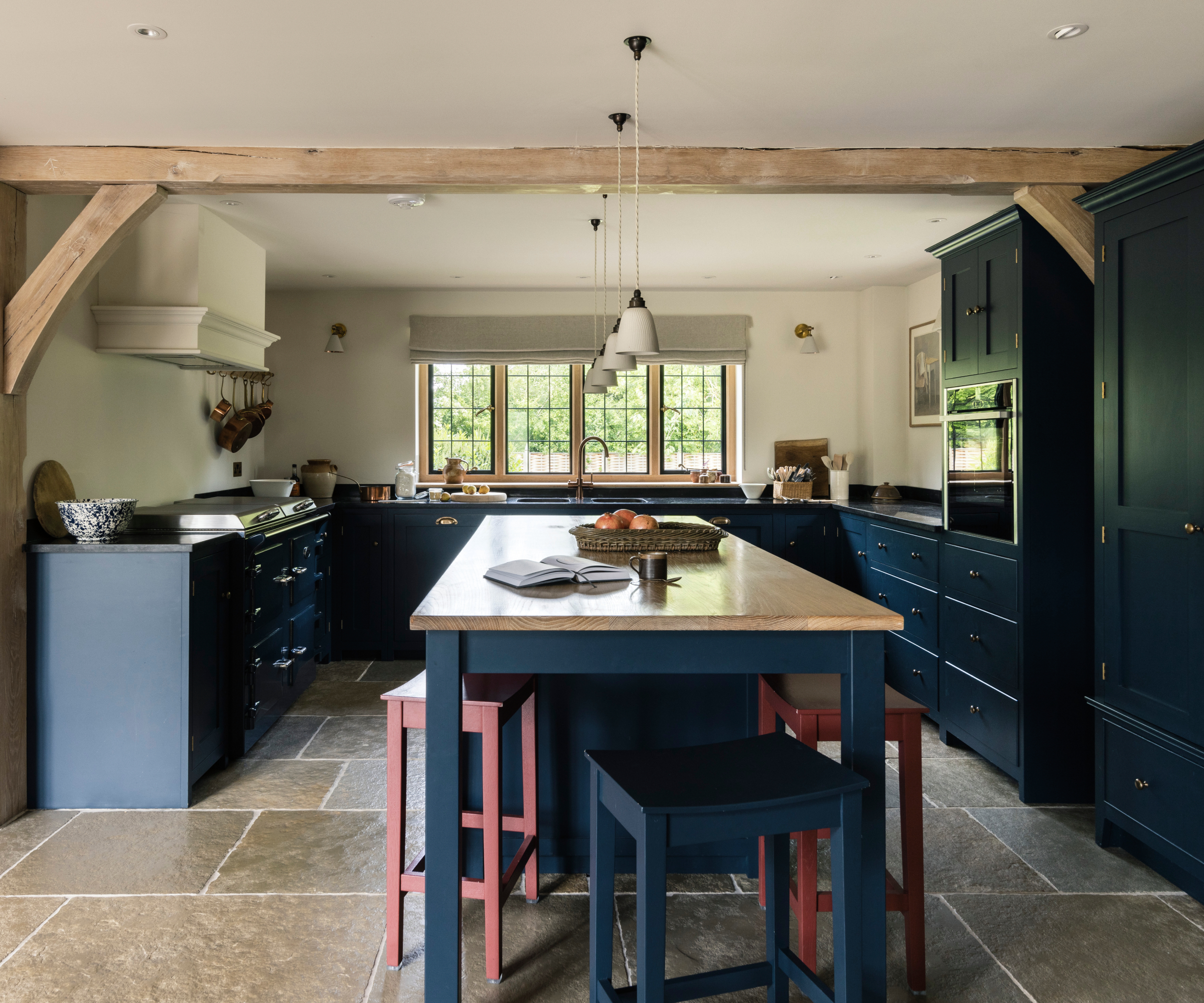kitchen in oak frame home with dark blue cabinets and large flagstone floor
