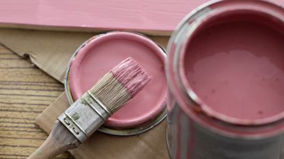A can of pink paint with a brush