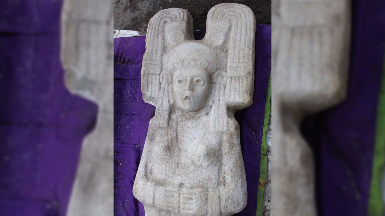 The statue depicts the woman wearing a necklace, earrings and large headdress.