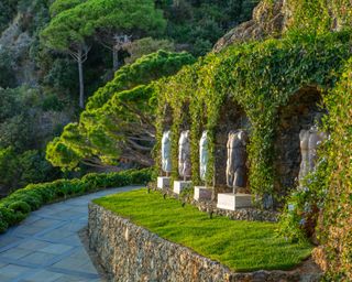 marble torso sculptures set along wall of terraced mediterranean garden