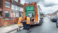Two bin collectors loading up the lorry with black bins