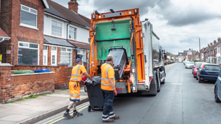 Two bin collectors loading up the lorry with black bins