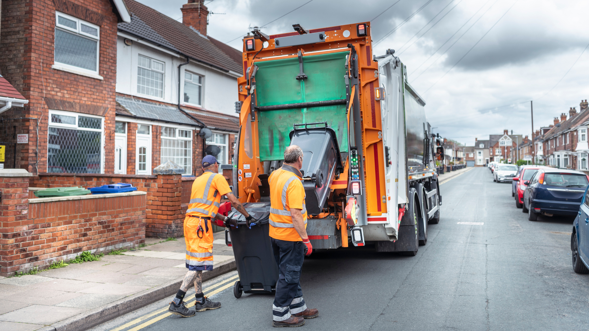 Two bin collectors loading up the lorry with black bins