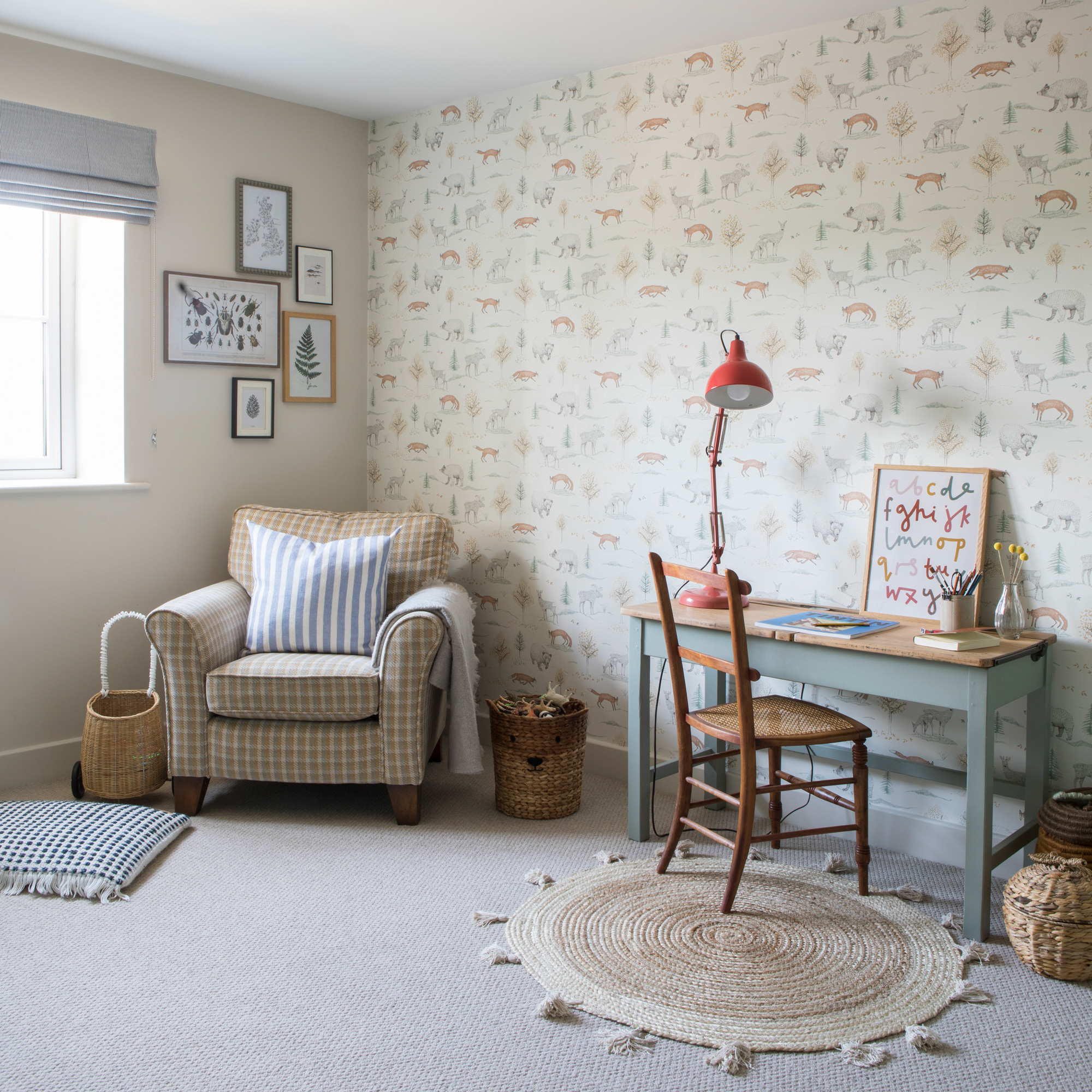 country cottage children's playroom with desk, chair and red lamp, armchair, rug and cute wallpaper