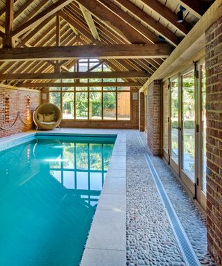 An example of pool landscaping ideas showing an indoor pool with wooden beams and a non-slip floor