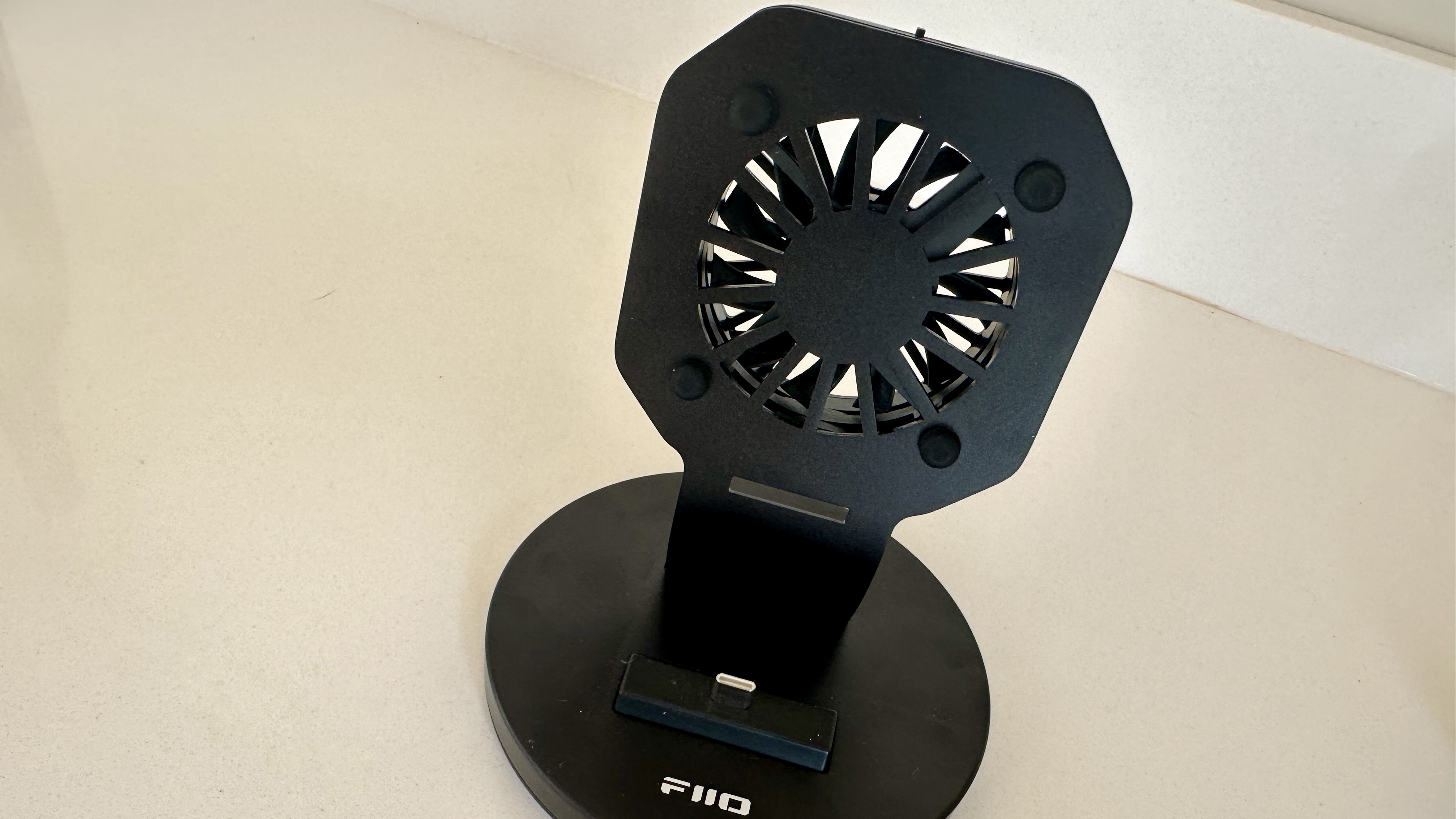 The FiiO M27 player with screen and dial showing, and content on the screen, on beige or yellow background