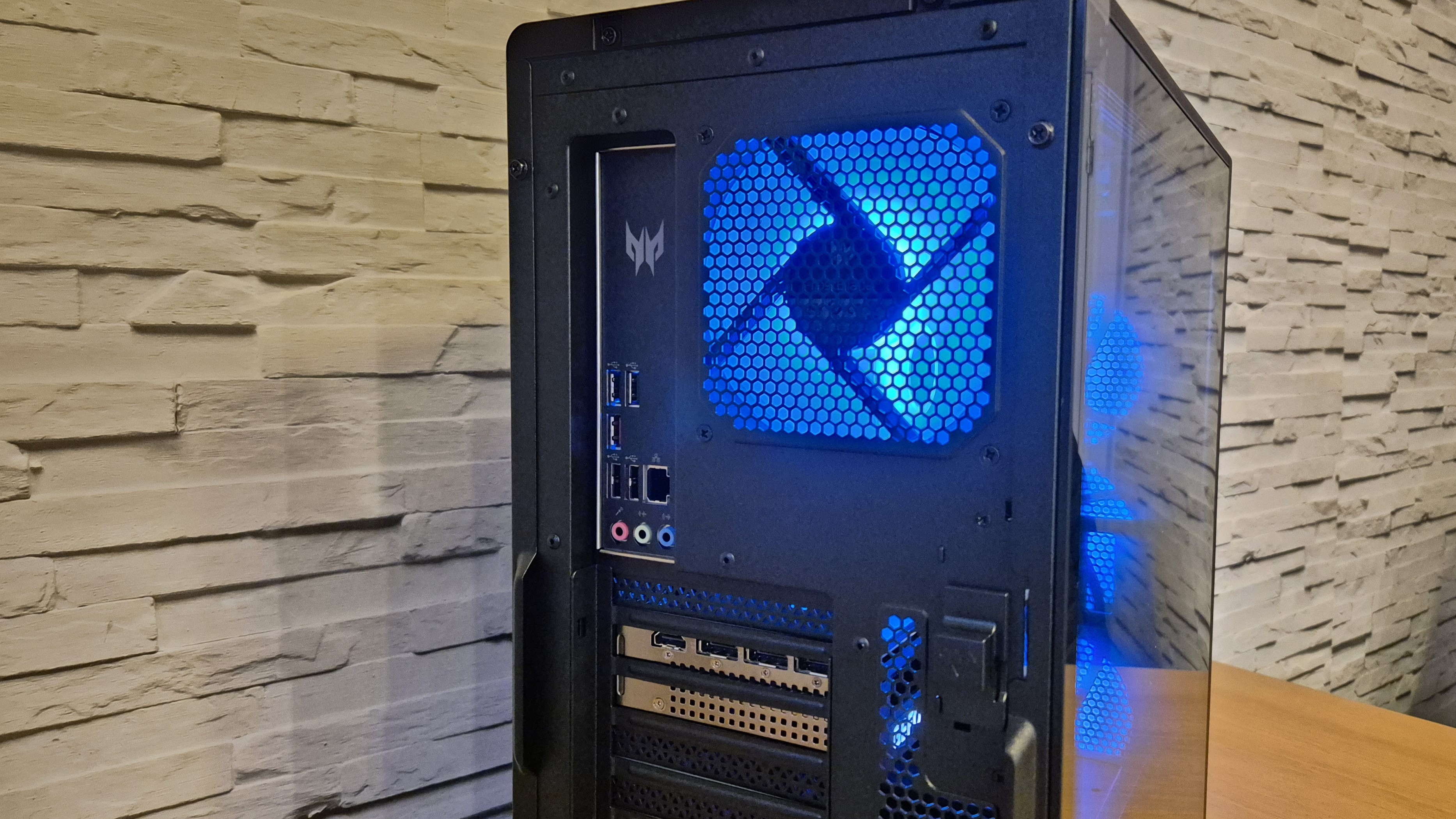 An Acer Predator Orion 5000 gaming PC sitting on top of a wooden surface infront of a white brick effect wall