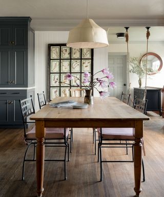 dining room with wooden table, metal chairs, wooden Windsor chair, cream pendant, gallery wall and leather swing seat