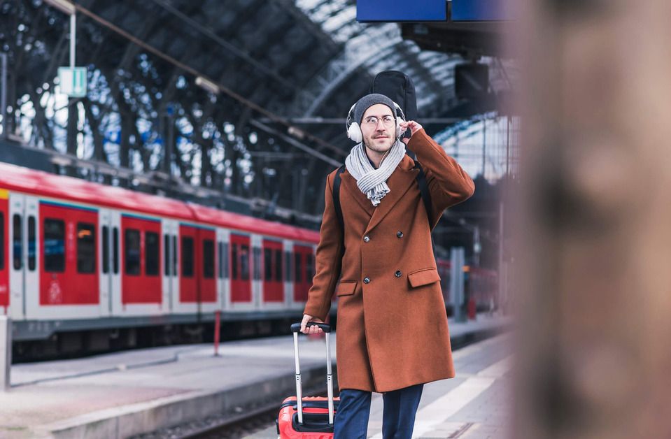 A man is pulling a small suitcase at the train station 