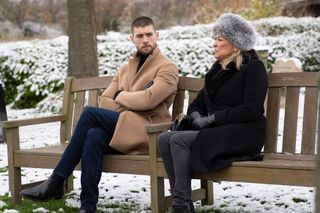 Joe and Kim sitting on a bench in the village with snow around them.