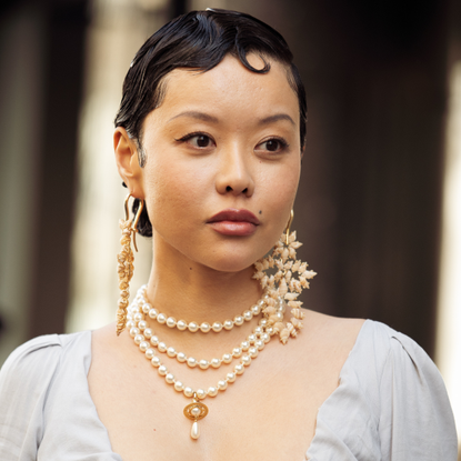 A guest wears grey long dress, pearl accessories and big statement earrings outside the Vivienne Westwood fashion show during the Womenswear Fall/Winter 2025/2026