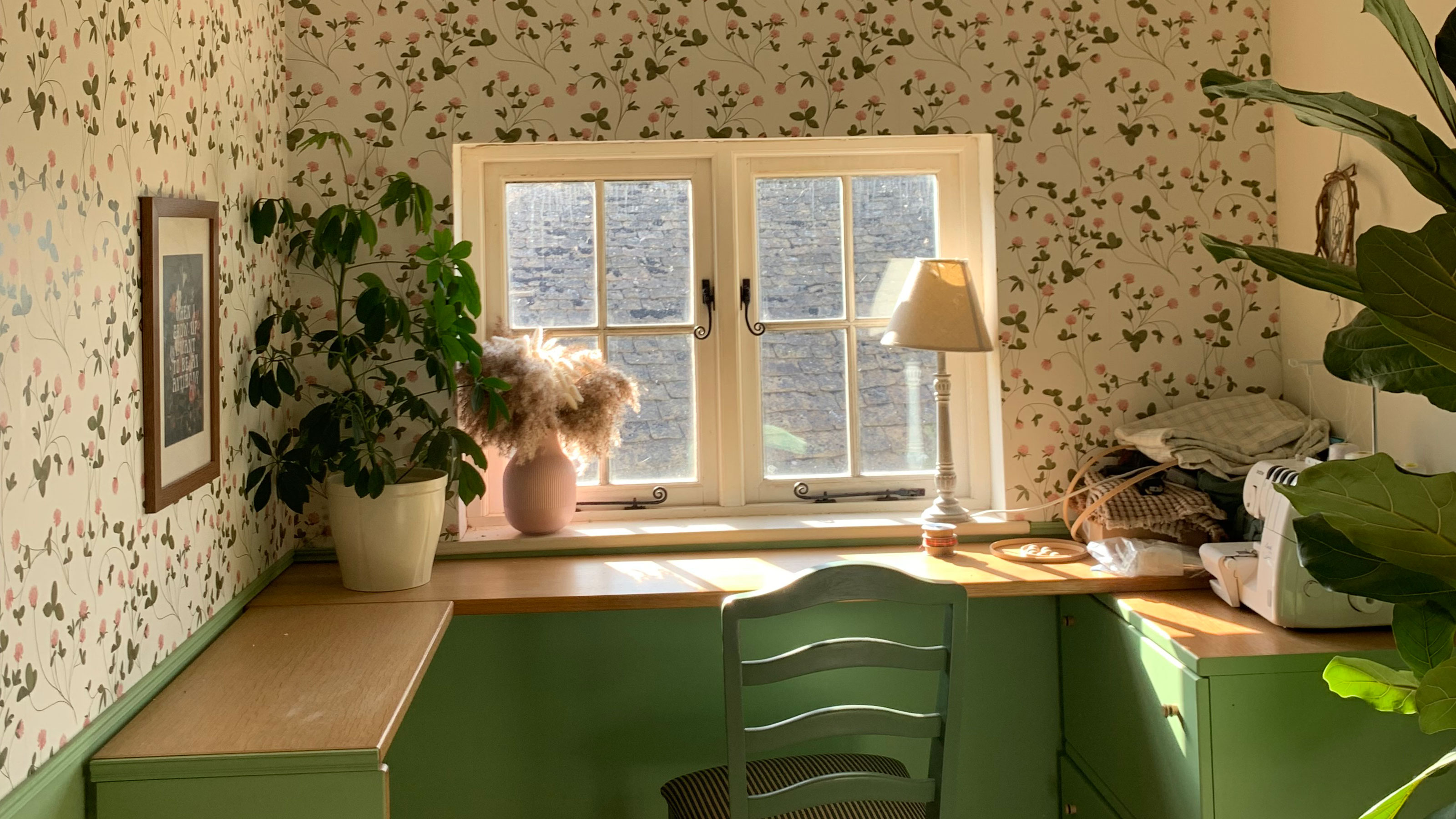 Home office with green desk and chair and walls covered in botanical printed wallpaper