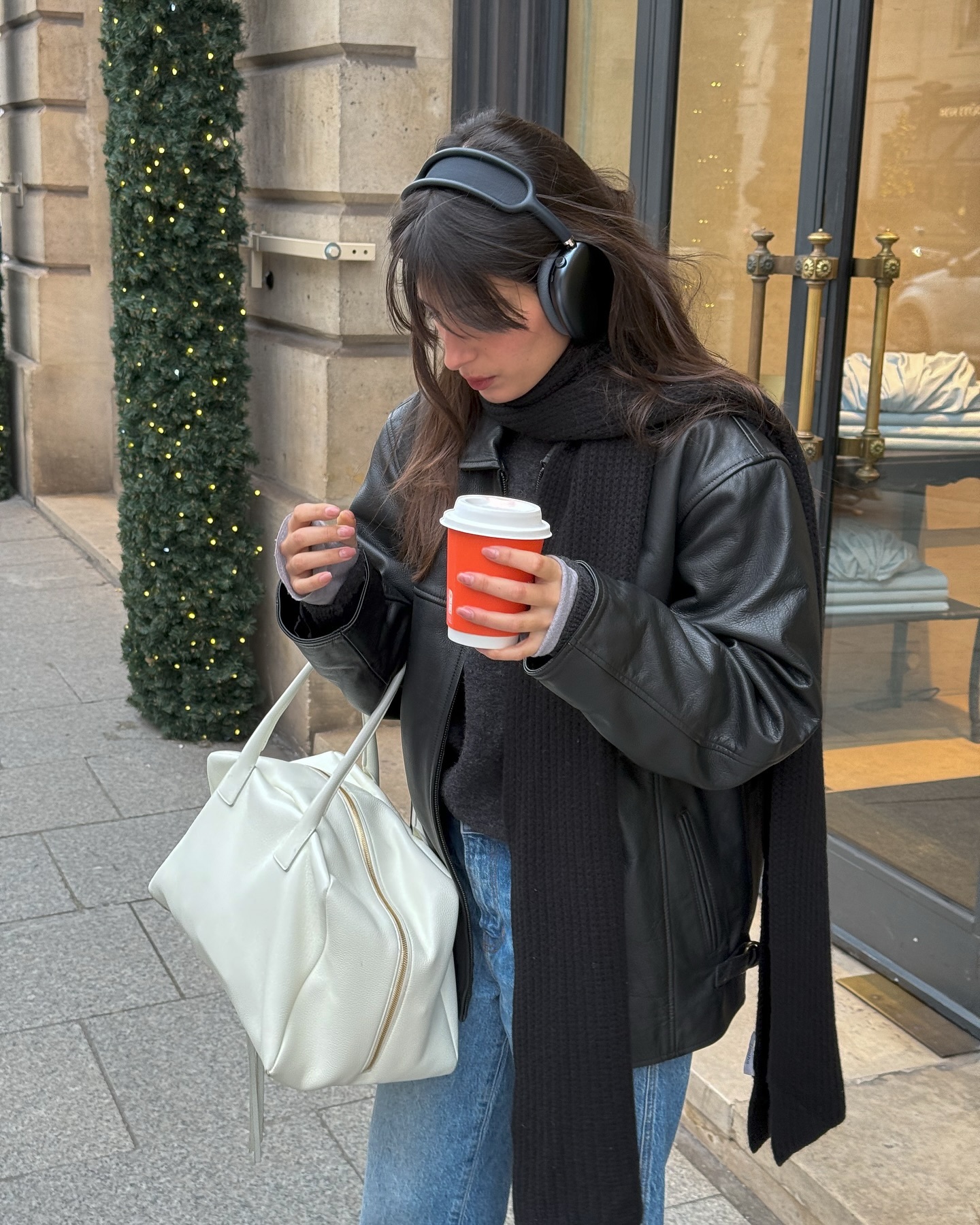 Tamara wears black leather jackets, black ribbed scarf, a white bowling bag, and blue jeans.