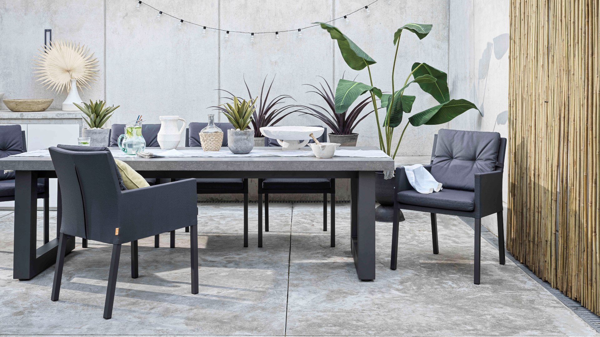 A black garden dining table and chairs on a paved patio