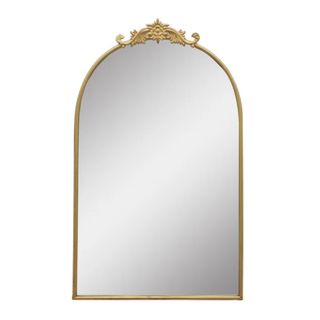 A gold arched mirror with a detailed top