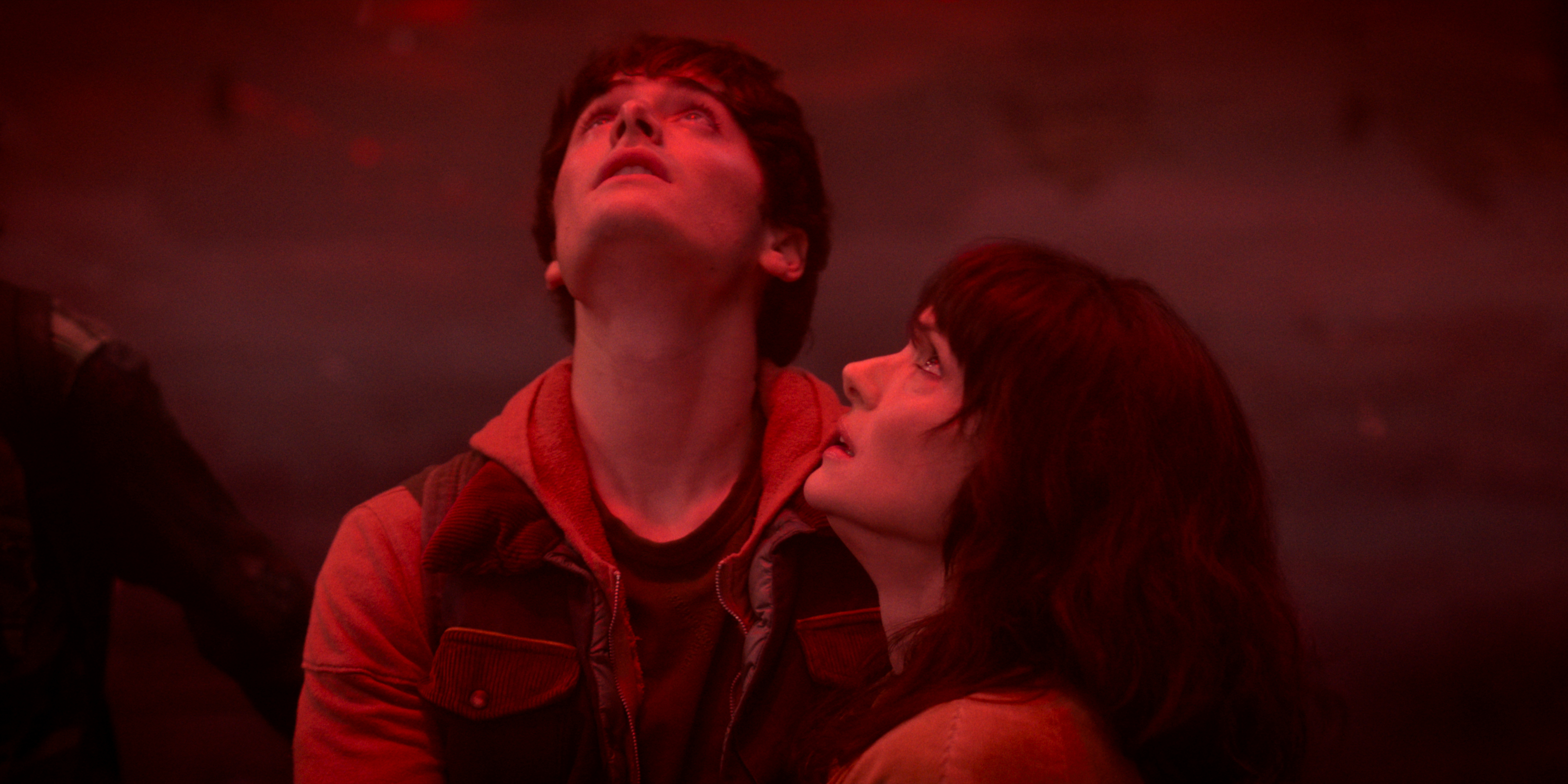 Noah Schnapp as Will Byers and Winona Ryder as Joyce Byers hugging each other in a red lit upside down in Stranger Things: Season 5