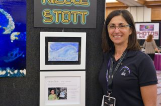 Nicole Stott poses with her original watercolor painted aboard the International Space Station in 2009.