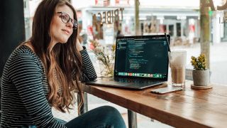 Beste laptop for programmering: En kvinne på kafe med en åpen laptop