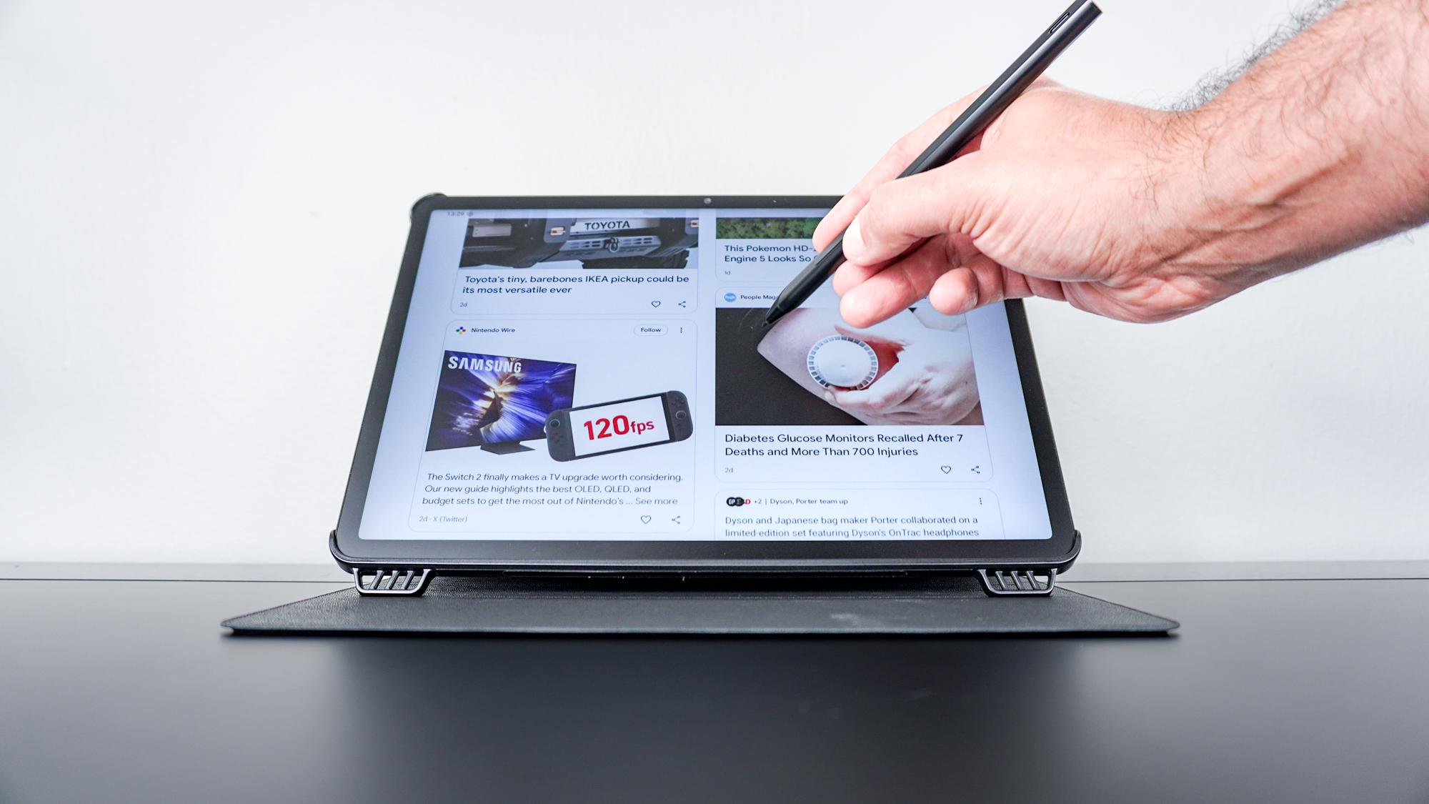 A person using the included stylus to scroll through stories in Google Discover on the TCL NXTPAPER 11 Plus