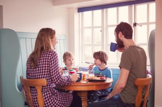 parents with two children sit around a circular table at home to eat