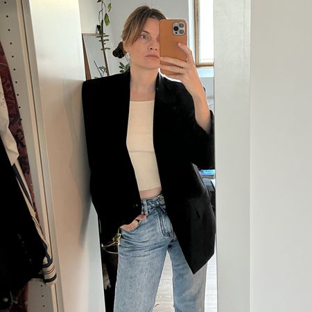 French writer and editor Eugenie Trochu poses for a mirror selfie wearing a chic repeat outfit with a black blazer, jeans, and a T-shirts