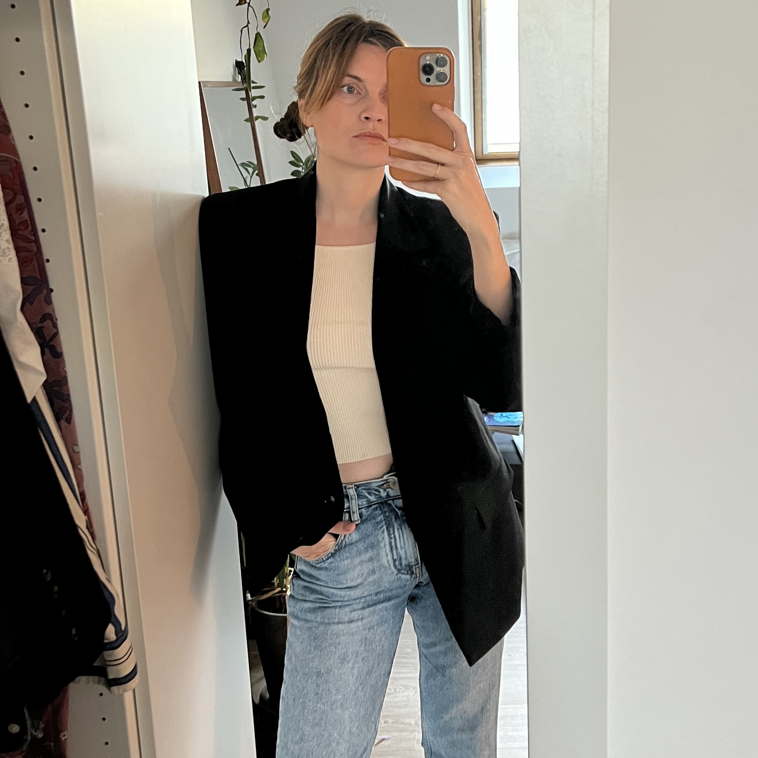 French writer and editor Eugenie Trochu poses for a mirror selfie wearing a chic repeat outfit with a black blazer, jeans, and a T-shirts