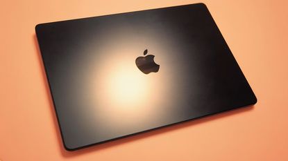 MacBook Pro M5 with orange background