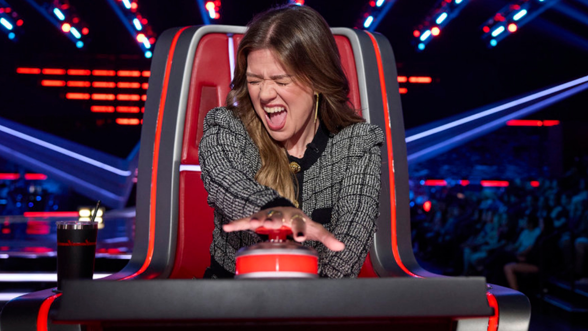Kelly Clarkson is shown making an excited face as she pushes her button on The Voice Season 30.