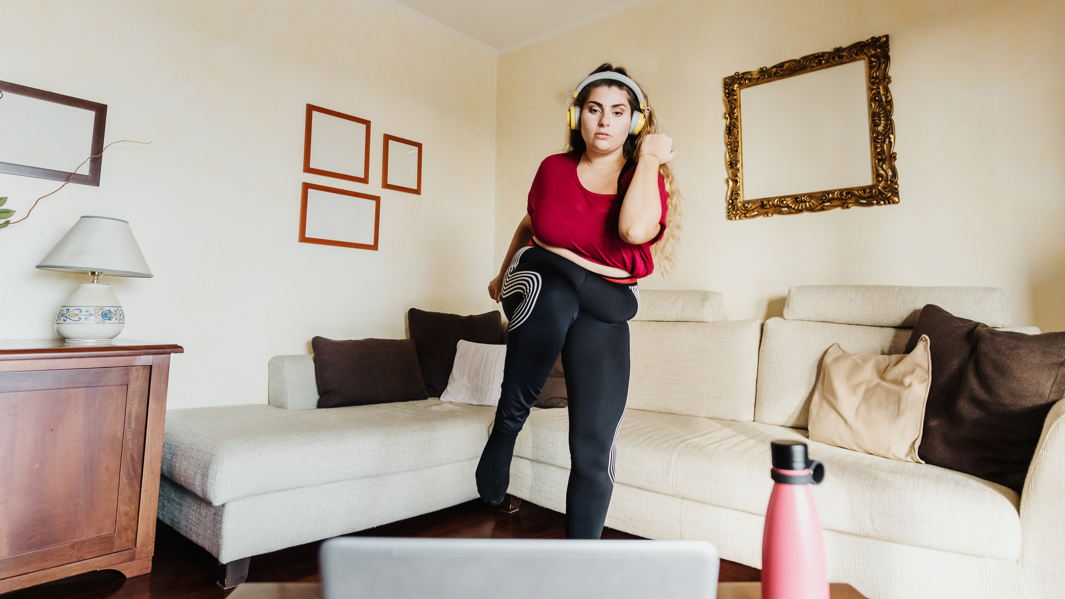 Woman exercises in living room in front of a laptop