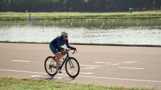 Woman cycling along a path alongside a pond in cycling event