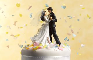 Bride and groom cake figurines surrounded by confetti