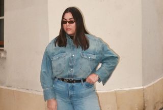 Woman wearing plus size jeans with matching denim shirt, standing on Paris street.