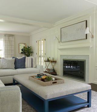 living room with marble fire surround and white corner sofas and white footstool