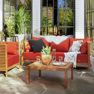 garden area with coffee table and red sofa with cushions and plant on pot