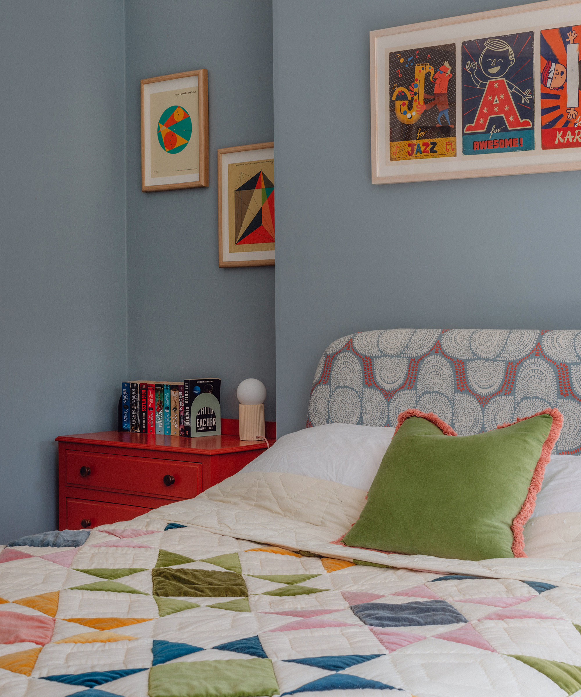 blue painted bedroom with colourful patchwork bed throw and vibrant wall art