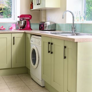 Light green kitchen with melamine tops and washer dryer under counter