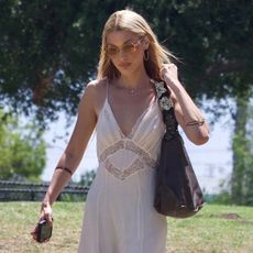 Bella Hadid was spotted at a park in Los Angeles. She wore cowboy boots with a summery white nightgown dress and a brown Valentino bag.