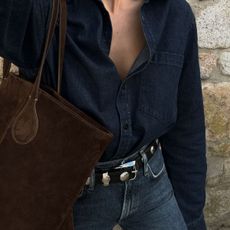 Woman wears denim jacket, blue jeans and studded Khaite Benny Belt