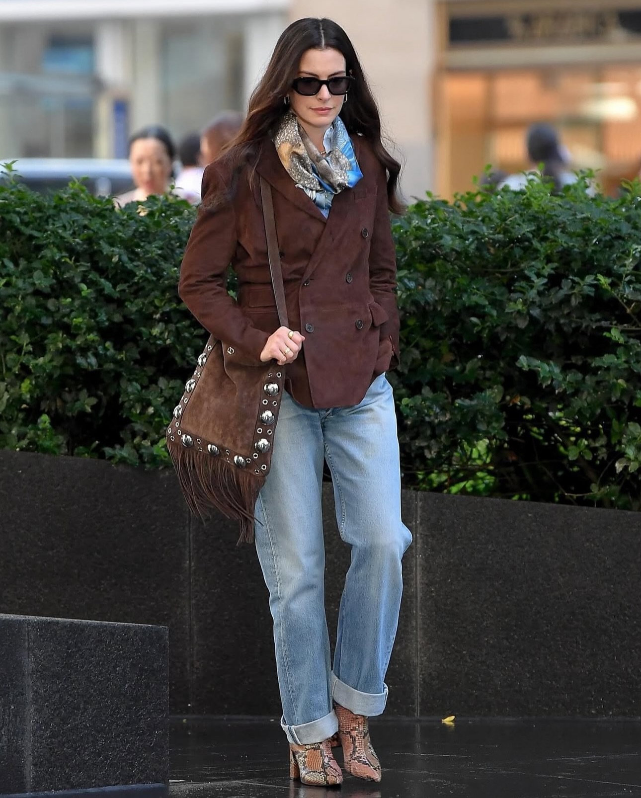 Anne Hathaway in The Devil Wears Prada 2 wearing Levi's vintage denim jeans with a brown suede jacket and snakeskin heeled boots
