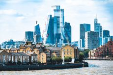 A view of the City of London with small residential houses and the Thames in the foreground.