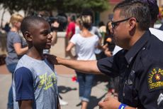 A police officer talks with a boy at the memorial at Dallas Police Headquarters