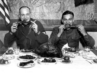 Two servicemen enjoy a public Thanksgiving dinner in New York City, 1918. Tens of thousands of wayward troops joined public dinners like this.