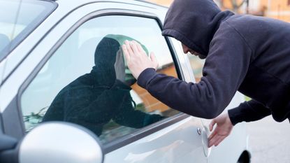 A thief peers into a car window