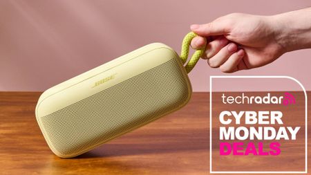 Person holding Bose Bluetooth speaker by carry strap with words 'TechRadar: Cyber Monday deals'