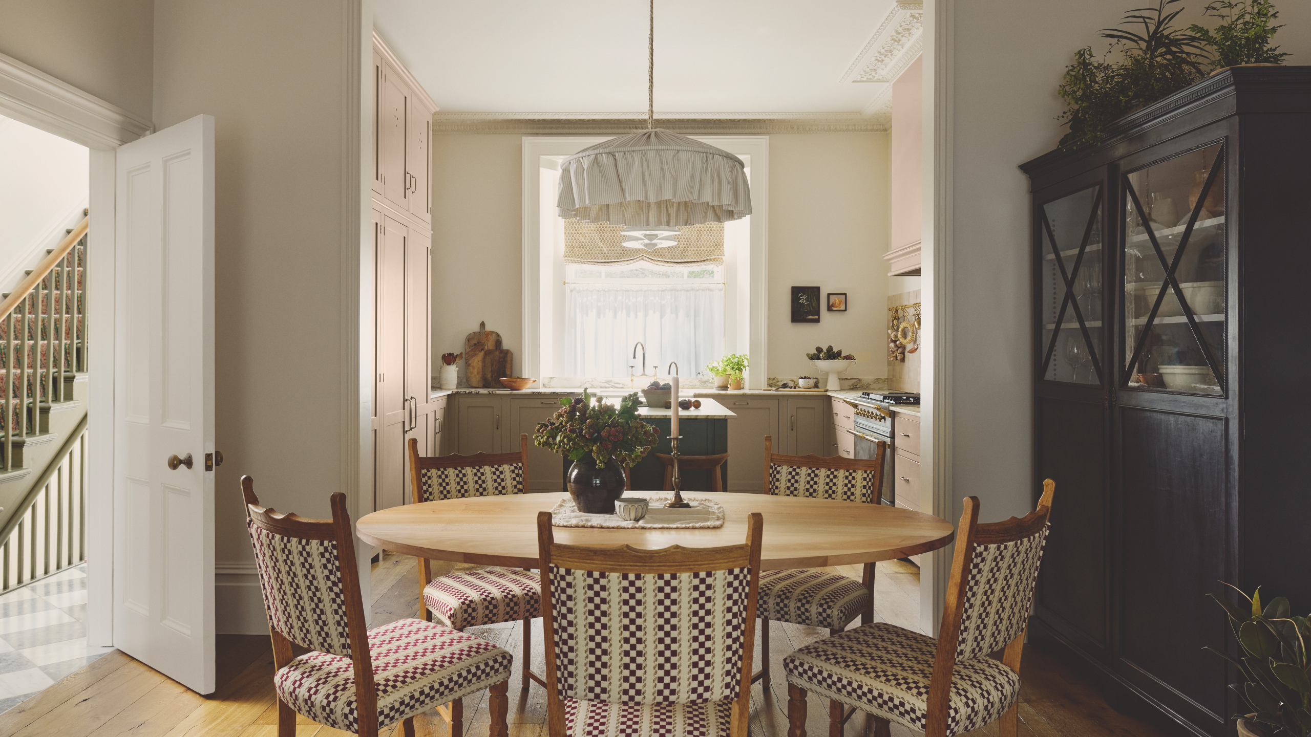 a kitchen and dining room with a table with five chairs, a black cabinet to the right, and a small kitchen in the background