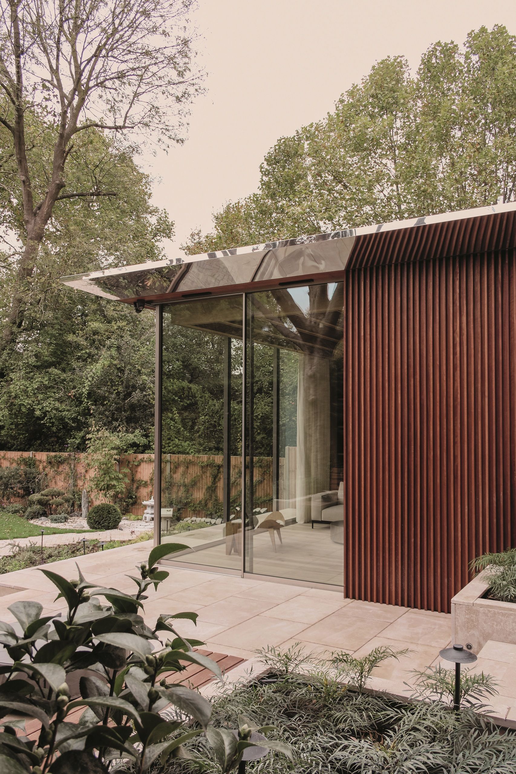 modern extension with slatted timber wall, glass walls, steel frame, tiled floors, and garden beds