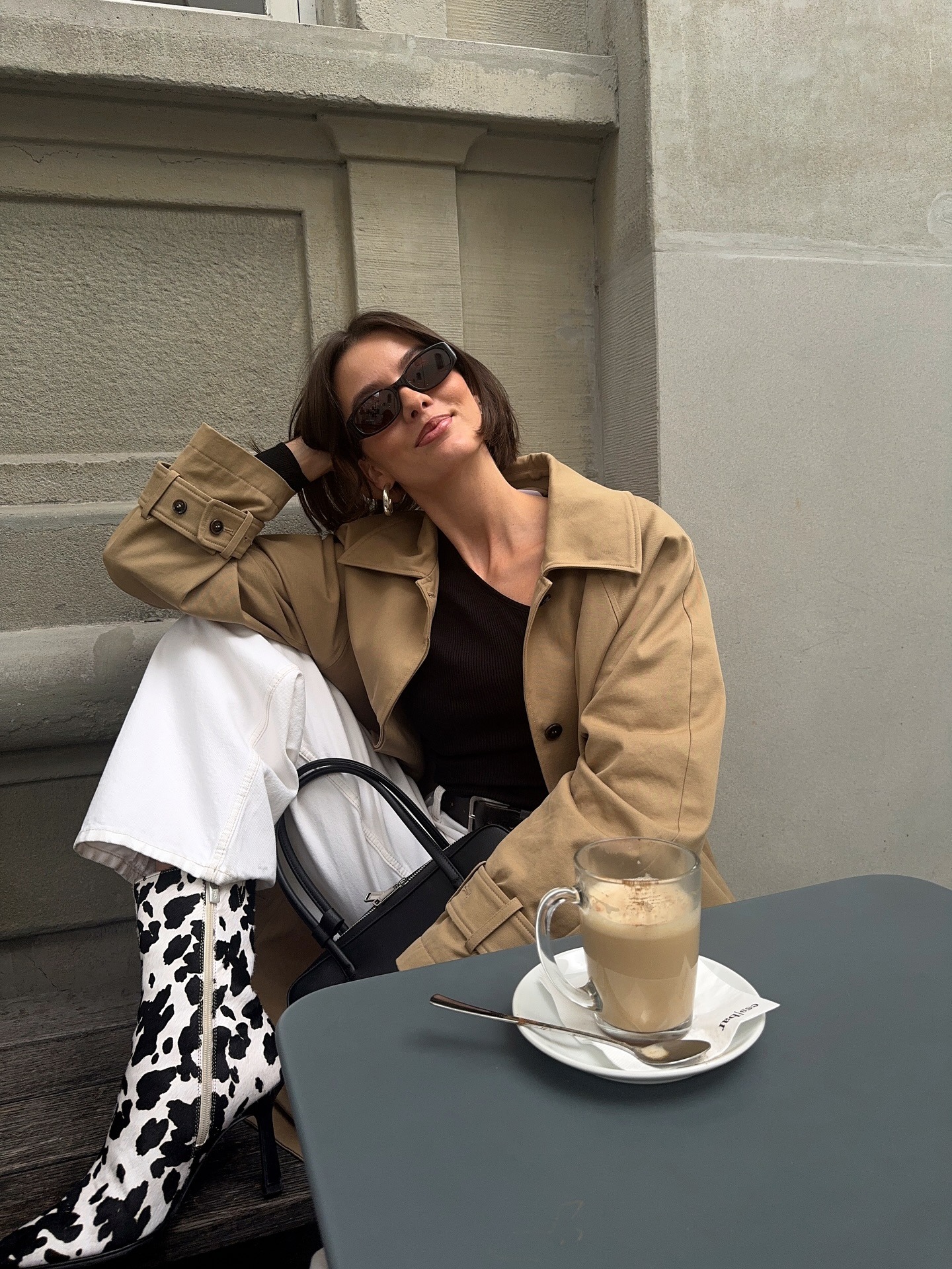 Influencer @maryljean wears cow print pony hair heels with a beige jacket and white jeans.