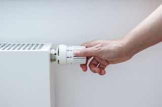 A person's hand adjusting radiator valve